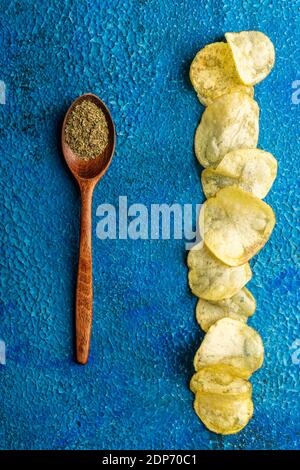 Homemade crispy potato chips with italian spices on the blue rustic background. Selective focus. Stock Photo