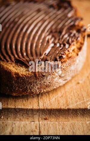 Slice of homemade bread with chocolate cream on the kitchen table for breakfast. Selective focus. Shallow depth of field. Stock Photo