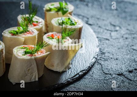 Tortilla rolls with vegetables, cheese and herbs on black rock Stock Photo