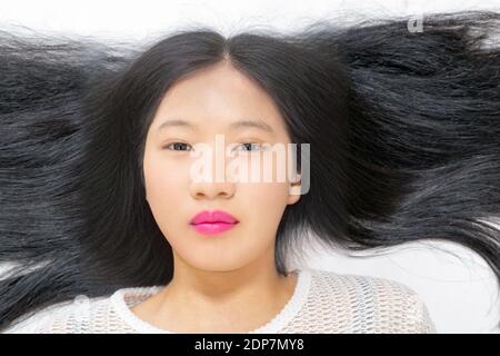 Teenage Asian high school girl laying down looking at camera, beauty portrait Stock Photo