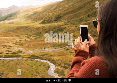 Woman takes a photo with smartphone of a landscape in Switzerland Stock Photo