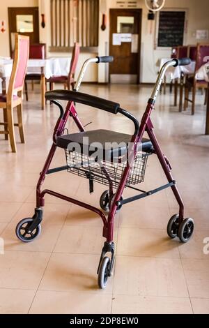 A rollator walker with a seat and a basket in an empty hall Stock Photo