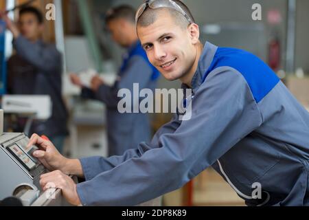 young workman operating machines in industrial shop Stock Photo