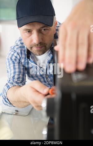 male technician repairing microwave oven Stock Photo