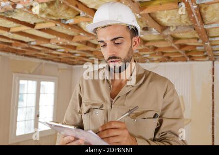 young builder making notes in a property Stock Photo