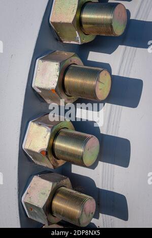 Large heavy galvanized industrial bolts and nuts mounted in a large metal flange on a pipe Stock Photo