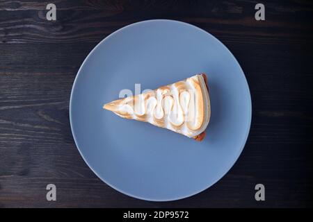 Plate of a Slice of Delicious Lemon Meringue Tart on Black Wooden Background Stock Photo