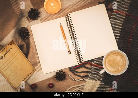 Home cozy atmosphere, copy space notebook with a pencil lies on a warm plaid, warm tones photo Stock Photo