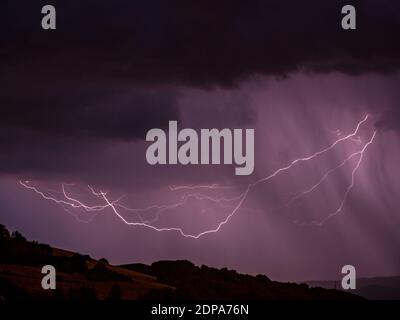 Storm with lightning over hilly landscape - Long exposure at night Stock Photo