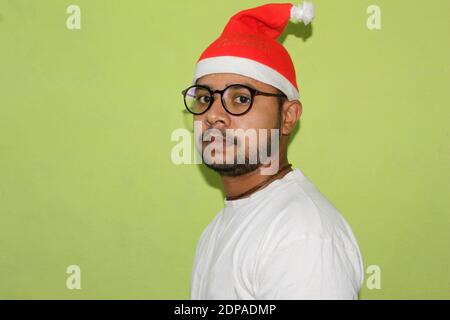Man with christmas hat expressing emotions portrait, Christmas Celebration over on green background, Selective focus with blur. Stock Photo