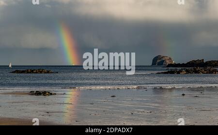 North Berwick, East Lothian, Scotland, United Kingdom, 19th December 2020. UK Weather: A double rainbow appears after rain striking the Firth of Forth and the Bass Rock and reflected in the wet sand on the beach Stock Photo