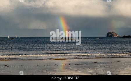 North Berwick, East Lothian, Scotland, United Kingdom, 19th December 2020. UK Weather: A double rainbow appears after rain striking the Firth of Forth and the Bass Rock and reflected in the wet sand on the beach Stock Photo