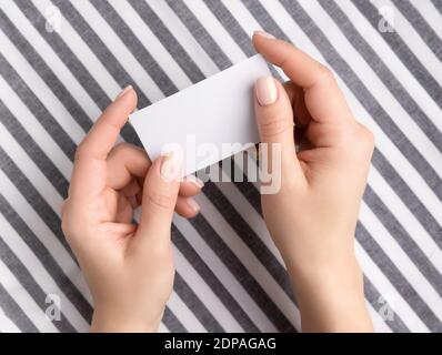 Manicured womans hands holding blank card. Flat lay, top view work at home office education concept. Stock Photo