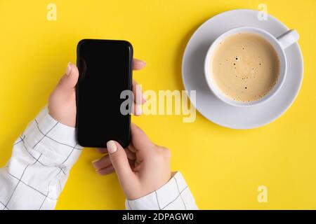 Manicured womans hands holding smartphone with blank screen. Flat lay, top view work at home office education concept. Stock Photo
