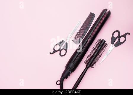 professional accessories of hairdresser with combs and sciccors on work desk pink background top view copyspace Stock Photo