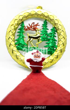 Santa Claus stands on a red carpet with gold Christmas ornaments on a white backgrounds Stock Photo
