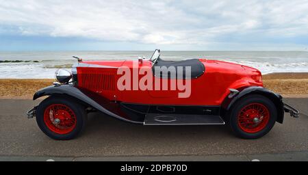 Classic Red Vauxhall Motor Car parked on seafront promenade with beach and sea in background. Stock Photo