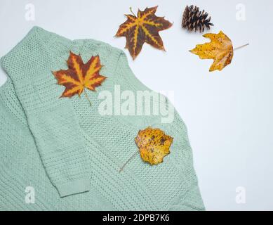 Autumn winter collection. Sweater, fallen leaves, pin cone on a white background. Top view Stock Photo