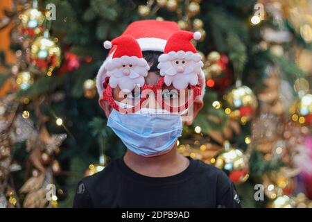 Kuala Lumpur, Malaysia. 19th Dec, 2020. A boy wearing a face mask and Christmas decorative eye glasses at a shopping mall, amid the coronavirus crisis. The cumulative reported coronavirus (COVID-19) cases in Malaysia surpasses China. Credit: SOPA Images Limited/Alamy Live News Stock Photo