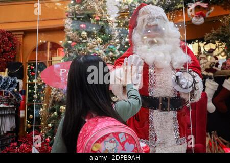 Kuala Lumpur, Malaysia. 19th Dec, 2020. A girl place her hand on a protective shield as she interacts with a man dressed as Santa Claus at a shopping mall, amid the coronavirus crisis. The cumulative reported coronavirus (COVID-19) cases in Malaysia surpasses China. Credit: SOPA Images Limited/Alamy Live News Stock Photo