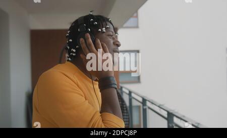 Portrait of african american black man with dreadlocks listening to the music on the balcony using headset. High quality photo Stock Photo