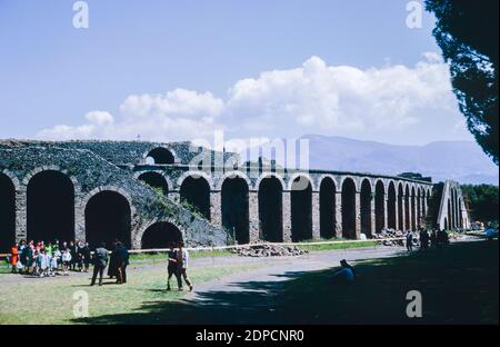 Archive scan of ruins of Pompeii comune destroyed by eruption of Mount Vesuvius in AD 79.  Exterior of Amphitheatre with visitors. May 1968. Stock Photo