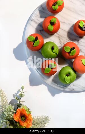 Marzipan sponge apples, green and red. Panoramic flat lay on marble board with winter flowers. Stock Photo