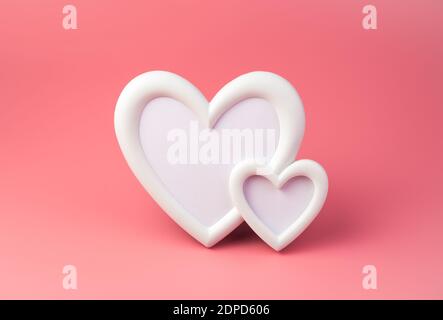White photo frame in the shape of two hearts on a pink background. Stock Photo