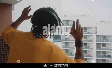 Positifity in the lockdown. African american black man with headset dancing on the terrace. . High quality photo Stock Photo