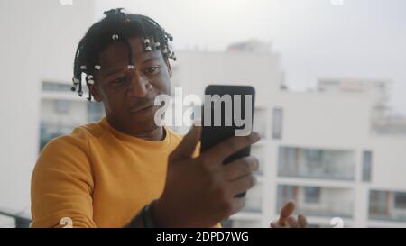 Video call. African american black man with dreadlocks having video call using smartphone. High quality photo Stock Photo