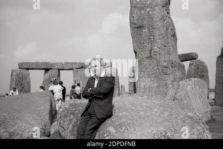 1950s, historical, people at Stonehenge, the famous prehistoric momument on Salisbury Plain in Wiltshire, England, UK. At this time, visitors could walk freely among the ancient sarsen stones and sit on them - as can be seen by a man here - without any issues, something that later would not be allowed. Stock Photo