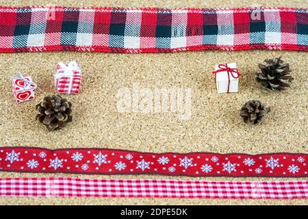 Christmas decoration elements organized on corkwood sheet. Tiny paper boxes, ribbons and small pine cones. Stock Photo