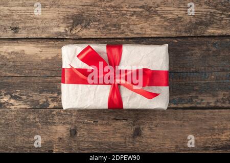 Gift box tied with a red ribbon on a wooden background. Top view, with space to copy. Stock Photo