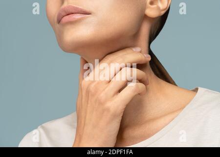 Closeup of sick woman having sore throat, tonsillitis, feeling sick, caught cold, suffering from painful swallowing, strong pain in throat, holding ha Stock Photo