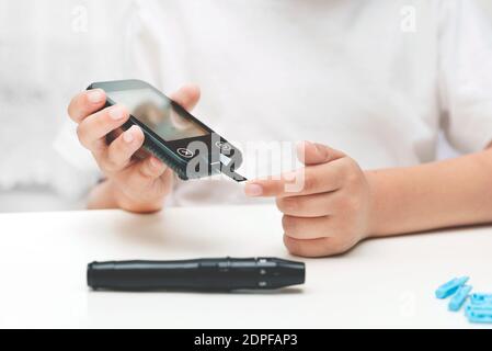 Young boy using glucometer, checking blood sugar level. Diabetes and children health care concept Stock Photo