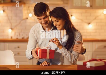 Young happy brunette woman unpacking holiday present from her smiling boyfriend Stock Photo