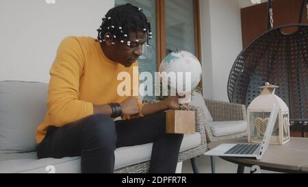 Vacation planning. Black man spinning the globe. Picking random location for the travel. High quality photo Stock Photo