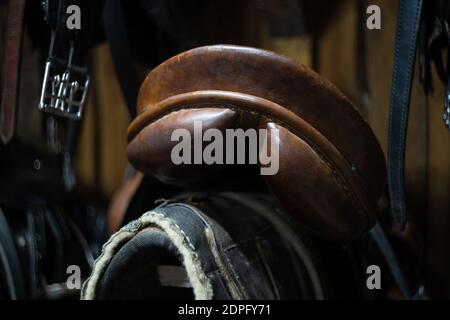 horse leather saddle hanging on a wooden wall Stock Photo