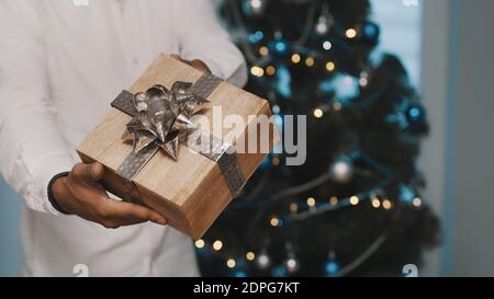 African american black man giving christmas gift in front of the christmas tree. High quality photo Stock Photo