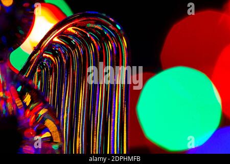Glass angel holding a heart and supporting a halo with fairy lights on the Christmas tree behind showing as bokeh Stock Photo