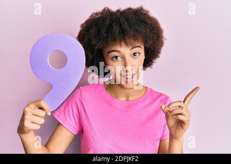 Young hispanic girl holding number nine smiling happy pointing with hand and finger to the side Stock Photo