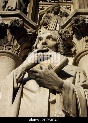 A statue of a saint clutching a book from the Cathedral of St. John the Divine. Stock Photo