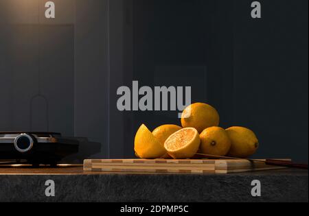 Front view of fresh whole and half lemons stacked on dark gray marble surface. Bright yellow citrus slices on blur kitchen background with copy space Stock Photo