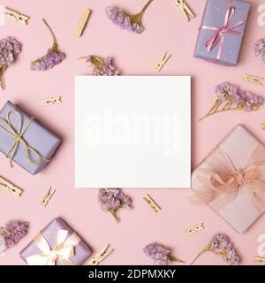 Empty memo paper with gift boxes, dry flowers, wooden clips on pink background. flat lay, top view, copy space Stock Photo