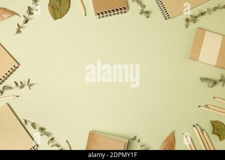 Brown kraft notebooks and wooden pencils with dry leaves on khaki green background. flat lay, top view, copy space Stock Photo