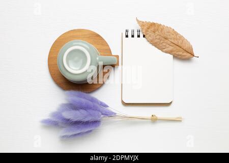 Empty notebook and mug cup with purple hares tail grass on white background. top view, copy space. Work and study place Stock Photo