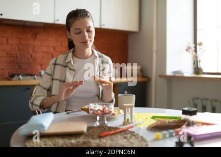 Attractive happy teenage girl making sandwich for breakfast before school in kitchen in morning Stock Photo