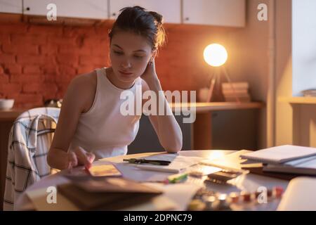 Young teenager it home clothes taking pause from preparing for exam and surfing on mobile phone in evening at kitchen Stock Photo