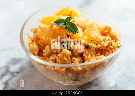 Healthy salad with couscous, tangerines, orange pieces, chickpeas, parsley and fresh mint.