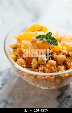 Healthy salad with couscous, tangerines, orange pieces, chickpeas, parsley and fresh mint.
